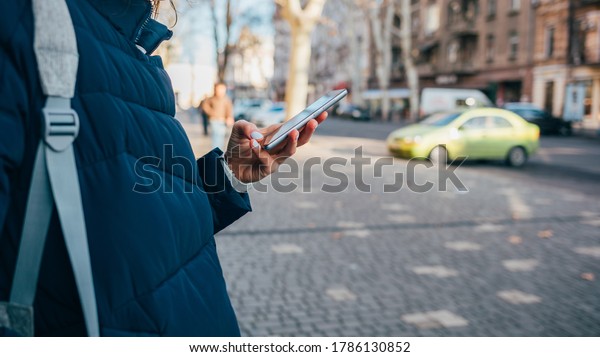 Woman holding\
phone in hand in winter\
street