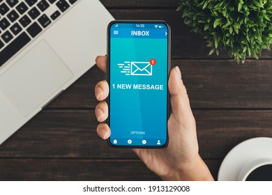 Woman Holding Phone With New E-Mail Message Inbox Sitting At Desk In Modern Office. Email Notification, Online Communication Application. Above View, Cropped, Closeup