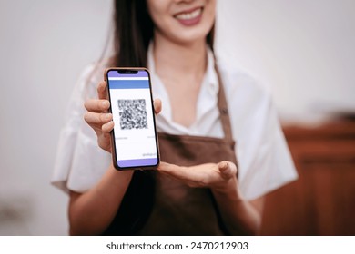 A woman is holding a phone with a QR code on it. She is smiling and she is happy