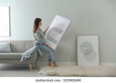 Woman holding picture near wall in room. Interior design - Shutterstock ID 1933903490