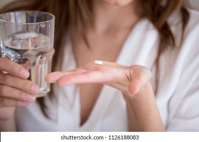 Woman Holding Pill And Glass Of Water In Hands Taking Emergency Medicine, Supplements Or Antibiotic Antidepressant Painkiller Medication To Relieve Pain, Meds Side Effects Concept, Close Up View