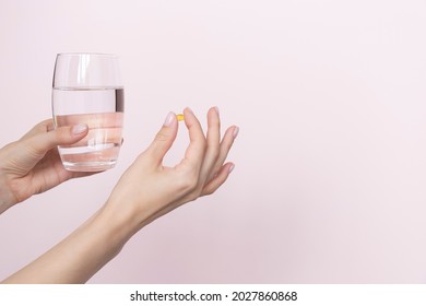 Woman holding pill and glass of water in hands taking emergency medicine, supplements or antibiotic antidepressant painkiller medication to relieve pain, meds side effects concept, close up view.  - Shutterstock ID 2027860868