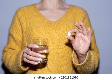 Woman holding pills and glass of water in her hands, taking emergency medications