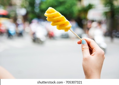 Woman Holding Pineapple Slice On A Wooden Stick