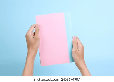 Woman holding pink book with blank cover for mockup isolated on blue background - Powered by Shutterstock