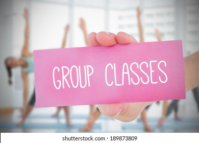 Woman Holding Pink Card Saying Group Classes Against Fitness Class In Gym