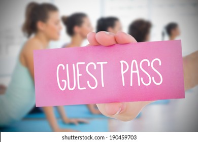 Woman Holding Pink Card Saying Guest Pass Against Yoga Class In Gym