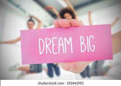 Woman holding pink card saying dream big against fitness class in gym