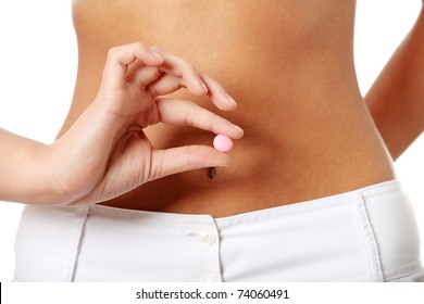 Woman holding pink pill against her nude belly. Diet supplement or contraception concept