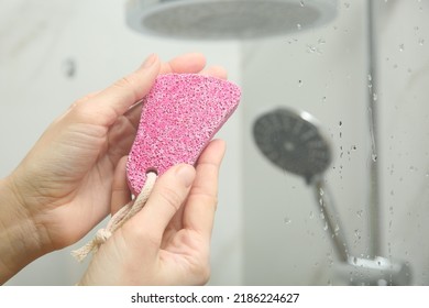 Woman Holding Pink Pumice Stone Near Shower Stall In Bathroom, Closeup. Space For Text