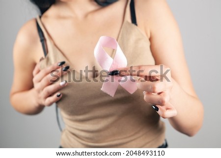 woman holding pink ribbon on gray background