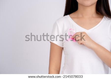 Woman holding a pink ribbon to raise breast cancer. Health care and medical concept.