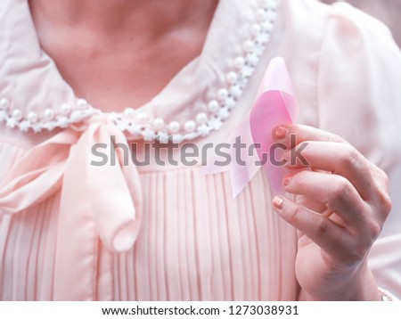 woman holding a pink ribbon as a symbol for breast cancer.