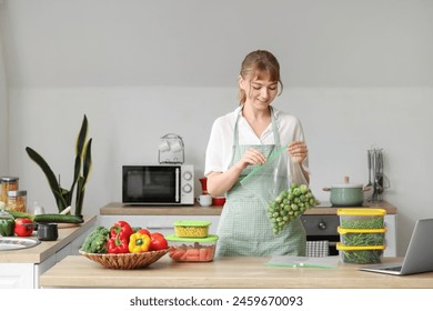 Woman holding plastic bag with brussels sprouts for freezing in kitchen - Powered by Shutterstock