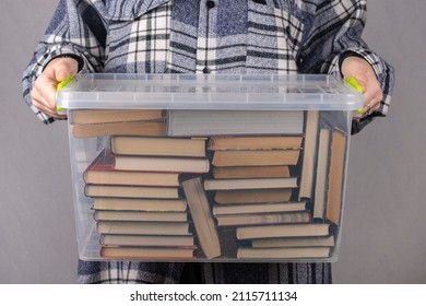 A Woman Is Holding A Plastic Box Full Of Books.