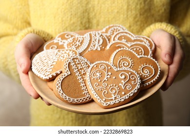 Woman holding plate with tasty heart shaped gingerbread cookies, closeup - Powered by Shutterstock