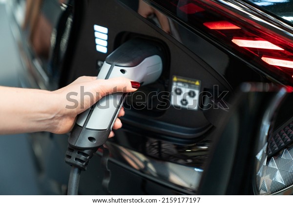 Woman\
holding plug of electric car charging station\
