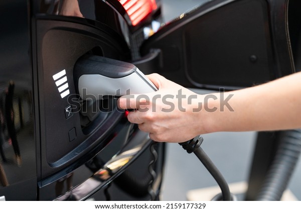 Woman\
holding plug of electric car charging station\
