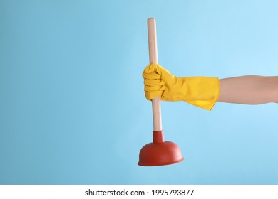 Woman holding plunger on turquoise background, closeup. Space for text