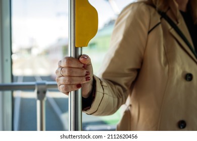 Woman holding pole in city bus. Hygiene risk when holding the handle in commuter. Traveling by public transportation