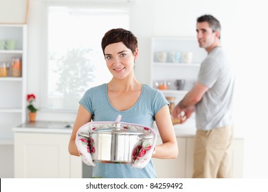 Woman Holding A Pot While Man Is Washing The Dishes In A Kitchen