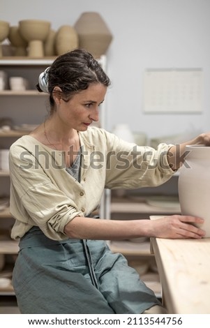 Image, Stock Photo Young female sitting by table and making clay or ceramic mug