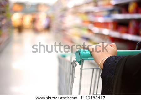 a woman holding pushcart shopping in supermarket in mall in Saudi Arabia Gulf Middle East