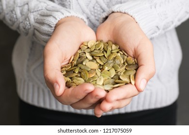 Woman Holding Raw Pumpkin Seeds, Closeup View