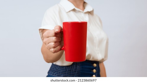 Woman Holding A Red Mug In Her Hand In Front Of Her On A White Background, Close-up