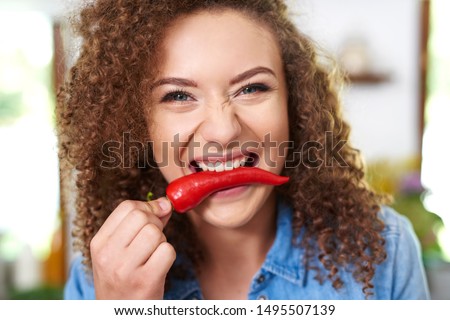Woman holding red pepper in her mouth