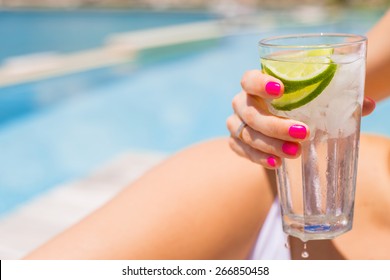 Woman Holding Refreshing Cold Drink While Sunbathing By The Pool