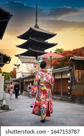 Woman Holding Retro Umbrella In Old Fashion Style Traditional Kimono, Walks  In The Middle  Park Of Garden Village In Autumn, Travel And Visit Japan On Incoming Sport Event