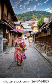 Woman Holding Retro Umbrella In Old Fashion Style Traditional Kimono, Walks  In The Middle  Park Of Garden Village In Autumn, Travel And Visit Japan On Incoming Sport Event