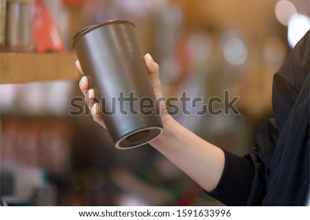 A woman holding reuse black coffee bottle in coffee cafe 