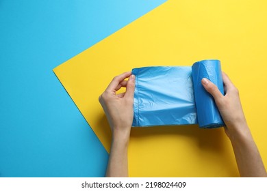 Woman Holding Roll Of Light Blue Garbage Bags Over Color Background, Top View. Space For Text