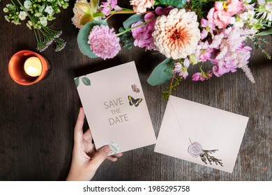 Woman holding a save the date card mockup by a bouquet of flowers