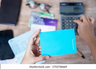 Woman holding savings deposit passbook and using calculator at home office tax and retirement planning concepts