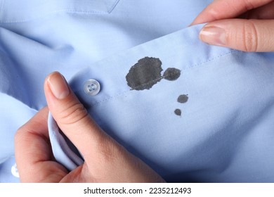 Woman holding shirt with black ink stain, closeup
