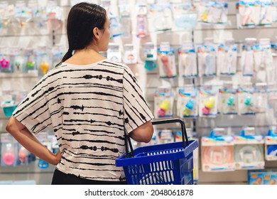 Woman Holding Shopping Basket. Mom Is Choosing Newborn Baby Product In Supermarket. Pregnancy And Shopping. Woman Choosing Baby Stuff At Baby Shop Store.