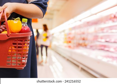 Woman Holding Shopping Basket In Supermarket