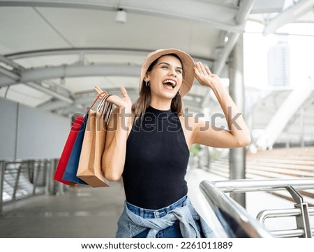 Woman holding a shopping paper bag. Happy woman with shopping bags enjoying in shopping. Consumerism, shopping, lifestyle concept.