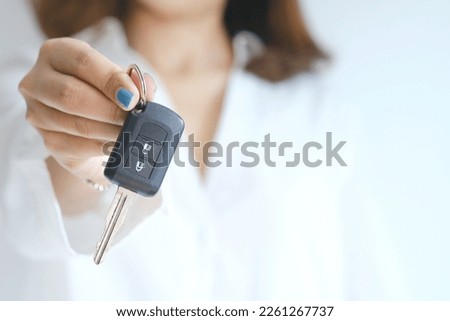 Woman holding and showing car smart key business concept and car loan