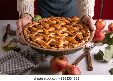 Woman holding and showing tasty cooked apple pie ready to be putting in the oven. Thanksgiving tart preparation, autumn bakery. Crispy weather sweets. Recipe - Powered by Shutterstock