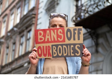 Woman holding sign with slogan Bans Off Our Bodies. Protester with placard supporting abortion rights at protest rally demonstration.