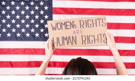 Woman Is Holding A Sign Womens Rights Are Human Rights US Flag On Background. Protest Against Anti Abortion Law. Women's Strike. Womens Rights Freedom.