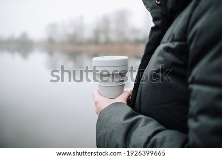 Woman holding a silicone collapsible cup, reusable coffee tumbler.