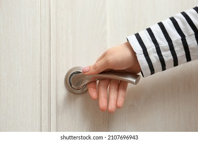 Woman Holding Silver Handle Of Light Wooden Door, Closeup