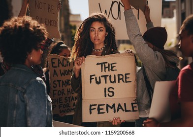 Woman Holding A Sing Saying The Future Is Female During A Rally Outdoors. Females Protesting For Their Rights.