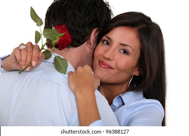 Woman Holding Single Red Rose And Hugging Husband