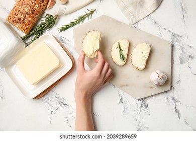 Woman holding slice of fresh bread with butter on light background